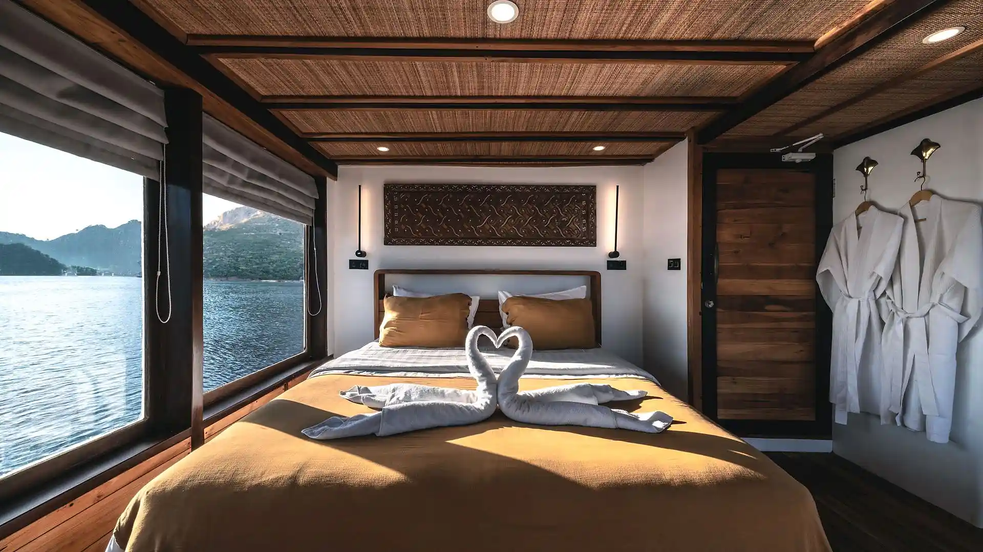 Master cabin with a queen bed, timber panelling and a large sea-view window